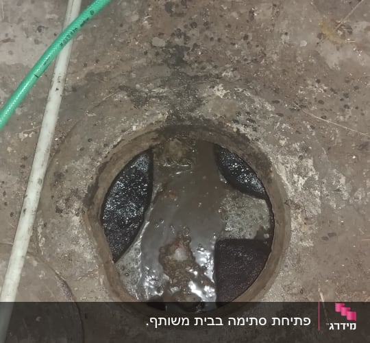 פתח ביוב עם צינור ירוק וכלי עבודה